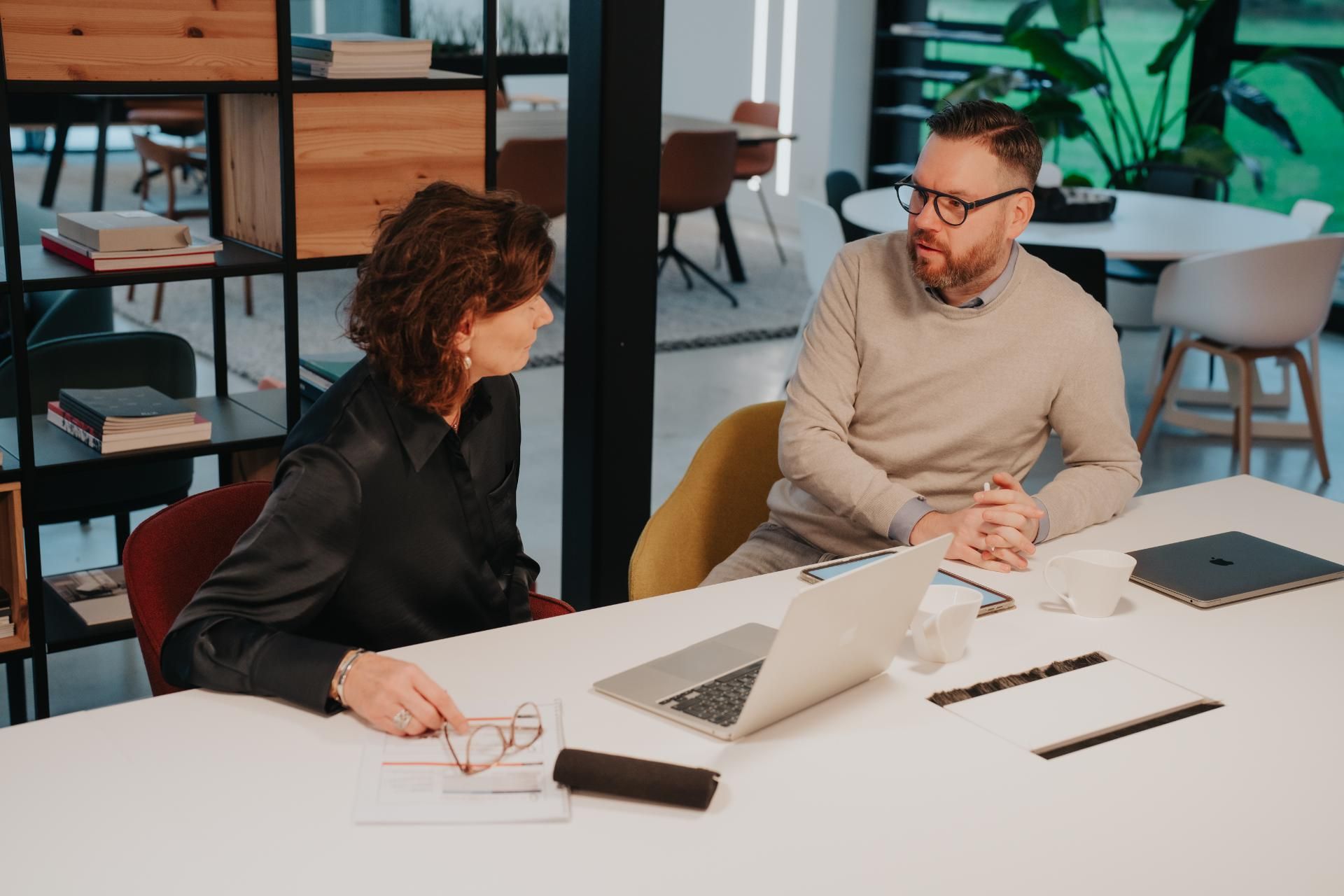 Twee coaches bespreken project aan lichte vergadertafel	